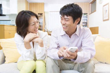 Asyalı çift akıllı telefon evde.