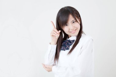 Asyalı üniformalı genç bir kadın parmağıyla işaret ediyor.