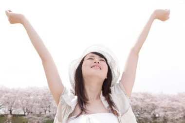 Parkta elleri havada genç bir kadın.