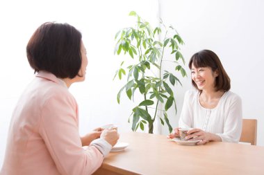 Kadın kahve içiyor ve bir bayan arkadaşıyla konuşuyor.