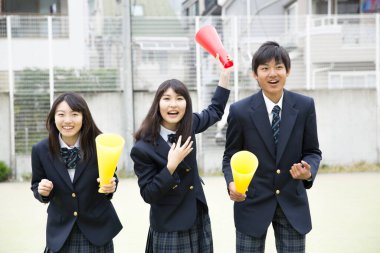 Dışarıda vakit geçirirken üniforma giyen mutlu Asyalı öğrenciler. 