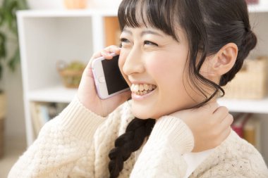 Güzel Asyalı genç bir kadın telefonda konuşuyor.