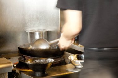 Şef mutfakta lezzetli bir sos hazırlıyor.