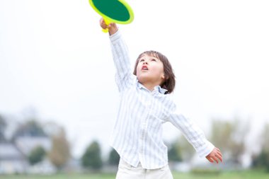 Mutlu küçük çocuk badminton oynuyor.