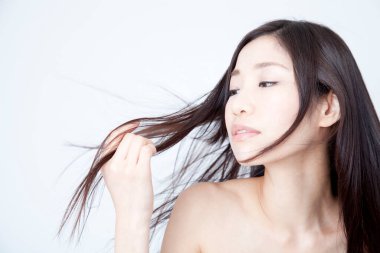 Güzel, genç Asyalı bir kadın saçlarına bakıyor, stüdyo fotoğrafı. 