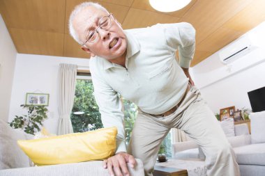 Yaşlı adam odada sırt ağrısı çekiyor.