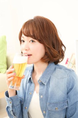 Neşeli Japon kadın evde bira içiyor.