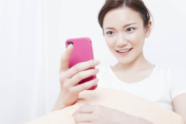 Genç Asyalı kadın akıllı telefon kullanıyor.