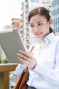Köprüde duran tabletli genç Japon kadının portresi.