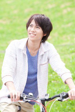 Parktaki bisikletli Asyalı adam.