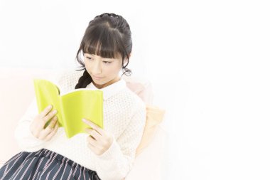 Genç Japon öğrenci kız evde kitap okuyor. 