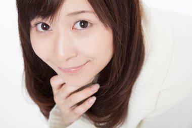 Beyaz arka planda kameraya bakan Asyalı kadın. 