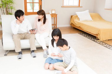 Genç veliler ve çocukları odada dijital cihazlar kullanıyorlar.