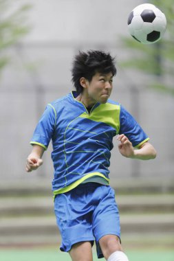 Genç Asyalı adam futbol oynuyor.