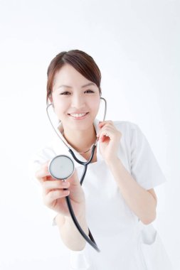 Beyaz cüppeli güzel Japon hemşirenin stüdyo portresi. Beyaz arka planda izole edilmiş neşeli bir doktor. 