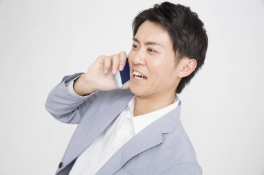 Beyaz arka planda cep telefonu olan Asyalı iş adamı