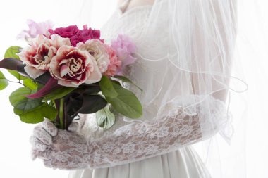 Gelin elinde güzel çiçeklerle düğün buketi tutuyor, yakın plan.      