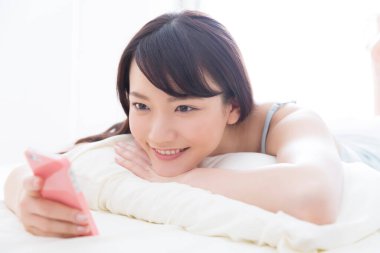 Smartphone ile yatakta yatarken kadın 