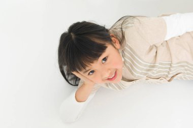 Beyaz zeminde yatan Asyalı küçük kız.