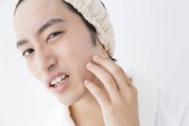 Cilt sorunu olan bornozlu bir adam, stüdyo fotoğrafı. 