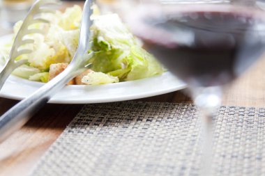 Lezzetli bir tabak taze salata ve bir bardak şarap.