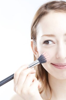 Makyaj yapan fırçalı kadın.