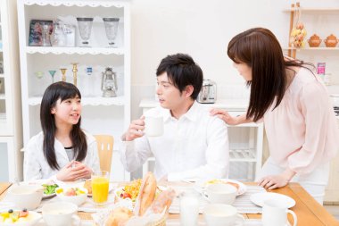 Üç kişilik aile birlikte kahvaltı yapıyor.