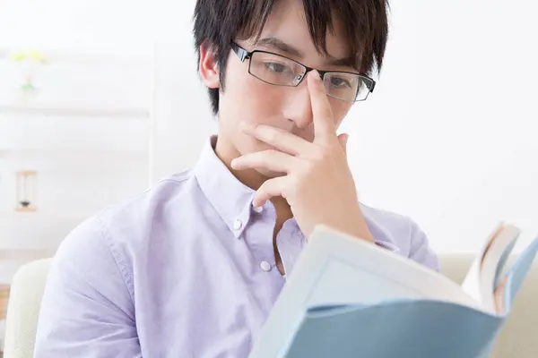 young man preparing for exams, reading book and studying