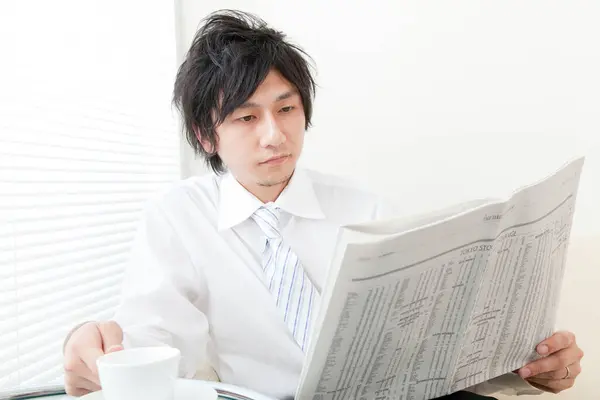 young asian businessman  reading newspaper