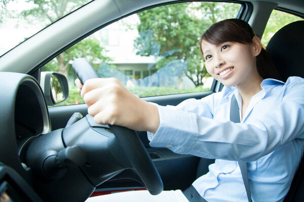 young happy asian woman driving car
