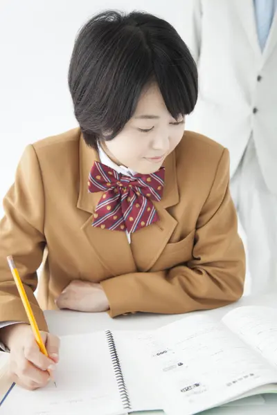 教師とクラスで勉強するユニフォルンを身に着けている若いアジアの少女 — ストック写真