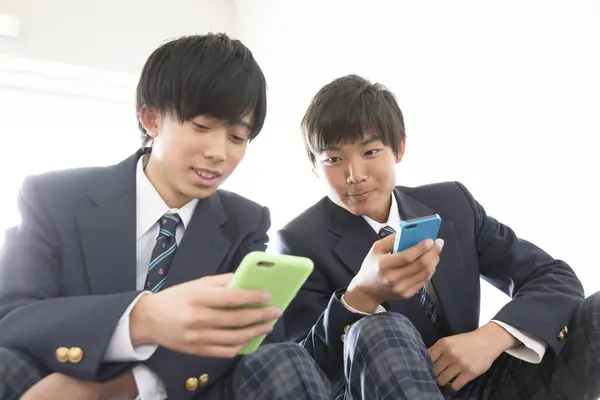 Два Азиатских Молодых Мальчика Школьной Форме Помощью Мобильных Телефонов — стоковое фото