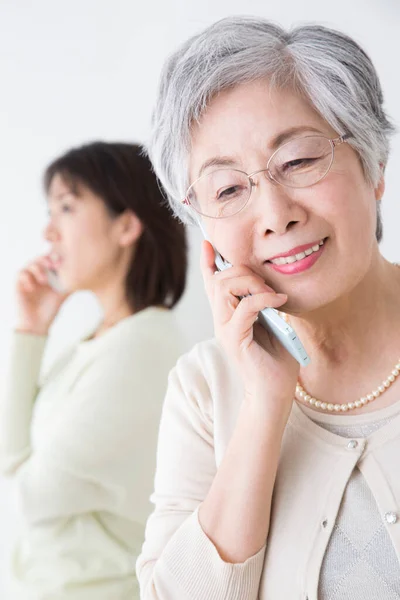 Asian Women Talking Mobile Phones Indoors — Stock Photo, Image
