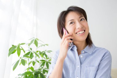 Gülümseyen ve akıllı telefondan konuşan bir kadın.