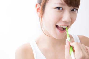 Genç bir kadın dişlerini fırçalıyor.