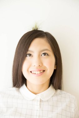 Kafasında küçük bir bitkiyle gülümseyen genç Asyalı kadın. 