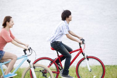 Yaz parkında bisiklet süren genç bir çift. Sağlıklı Yaşam Tarzı Konsepti.