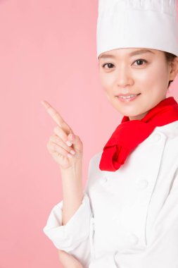 Genç Asyalı kadın şef üniforması giyiyor.