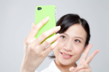 Yeşil kapaklı akıllı telefonu olan genç bir kadın.