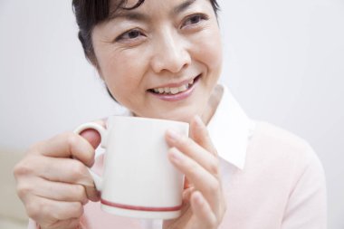 Asyalı son sınıf öğrencisi çay içiyor. 