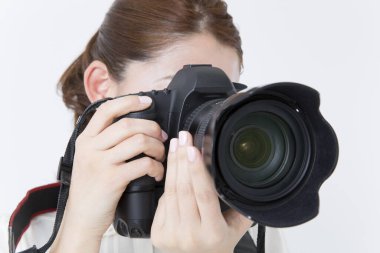 Kamerayla poz veren genç Asyalı kadın fotoğrafçı