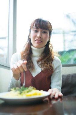 Asyalı kadın mutfakta lezzetli makarna yiyor.