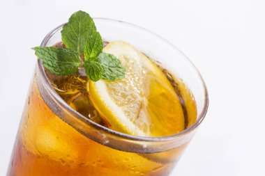 Beyaz zemin üzerinde limon ve nane olan bir bardak buz.