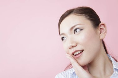 Pembe arka planda gülümseyen Asyalı genç bir kadının portresi