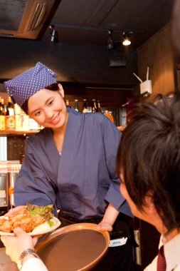 Genç Asyalı garson bir ziyaretçiye hizmet ediyor.