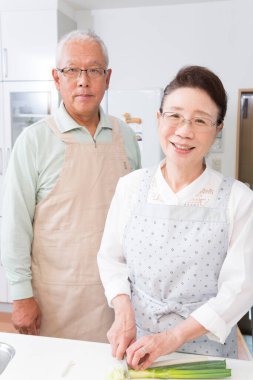 Gülümseyen çift mutfakta sebze hazırlıyor.