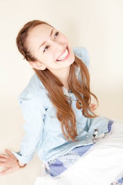 Stüdyoda yerde oturmuş gülümseyen genç bir kadının portresi. 