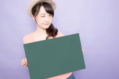 Boş yeşil bayrağı olan gülümseyen Asyalı genç kadın.