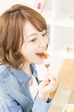 Güzel Asyalı kadın evde yemeğin tadını çıkarıyor.