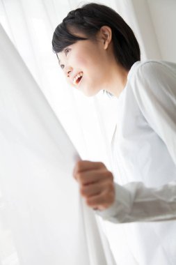 Pencere perdesi tutan Asyalı kadın